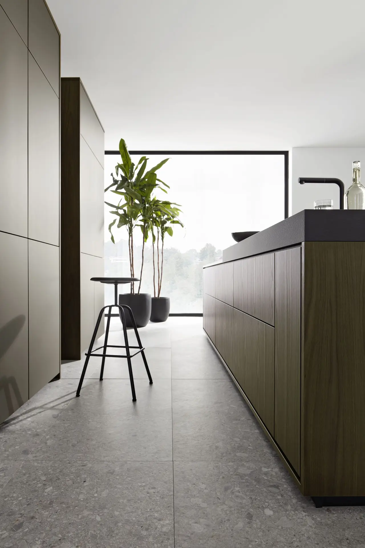 Handleless kitchen with dark grey units and a long island beside floor-to-ceiling windows